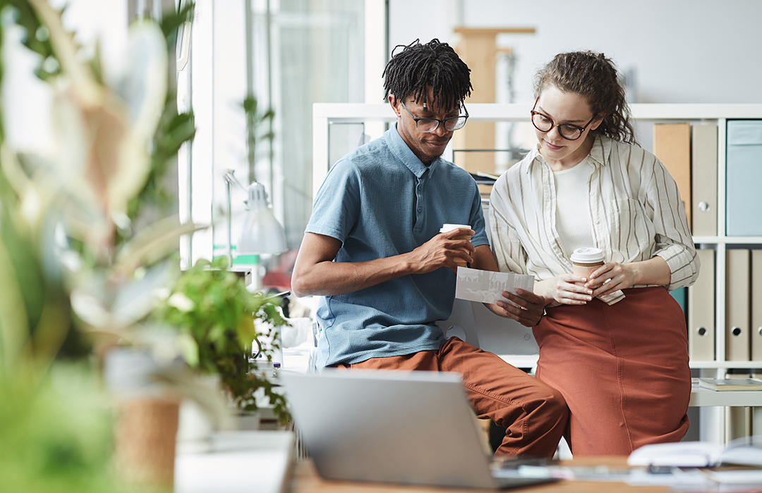 OTM_Image_Couplewithcoffee Man and woman holding coffee looking at laptop